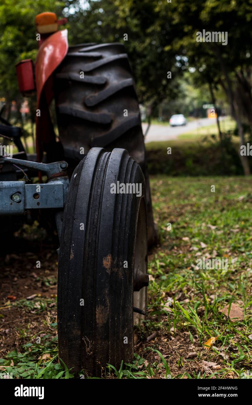 Pneumatici usurati di una fattoria abbandonata rossa molto vecchia trattore in un'azienda agricola di campagna Foto Stock