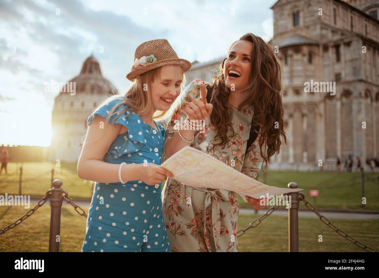 Sorridente mamma e bambino alla moda con mappa per esplorare le attrazioni vicino alla Cattedrale di Pisa. Foto Stock