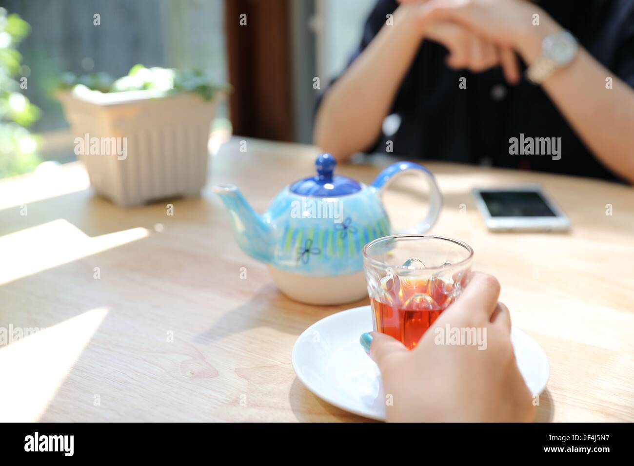 Donna mano con tè e smartphone che parla business in caffè negozio Foto Stock