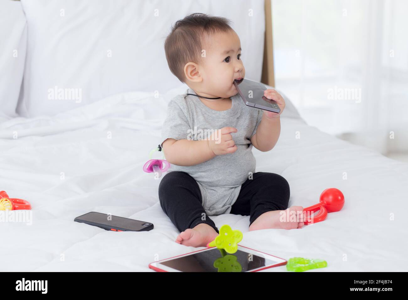 Ritratto di carina bambina seduta con accogliente sul letto in camera da letto, felicità del bambino, neonato 6-11 mesi con innocenza ed espressione con ch Foto Stock