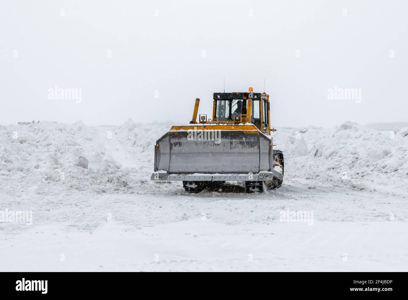 Il bulldozer giallo rimuove le nevi in una tempesta di neve grave in inverno Foto Stock