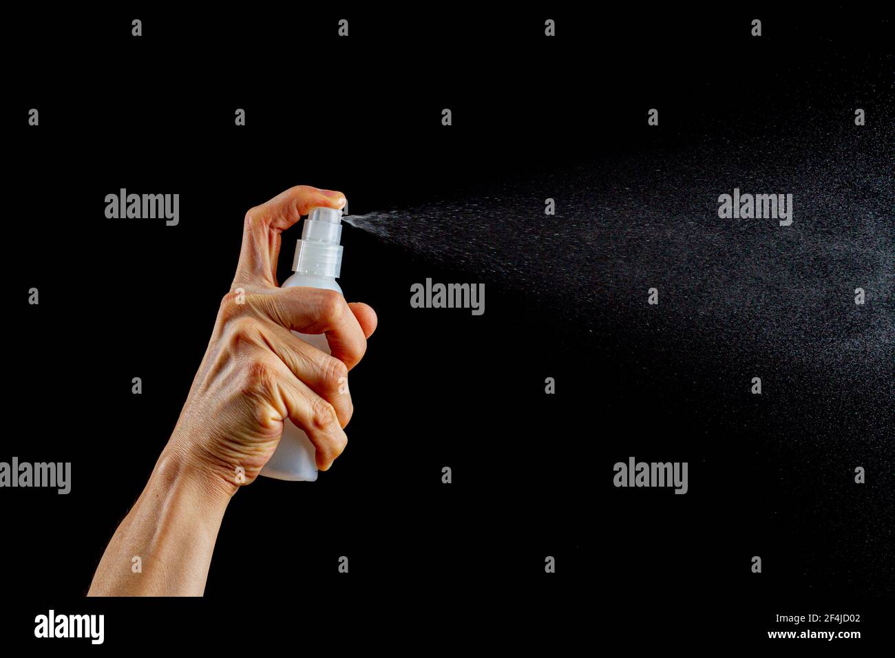 Una donna caucasica sta tenendo un piccolo spruzzatore di plastica fine nebulizzazione flacone e premendo il pulsante superiore per spruzzare liquido incolore. Immagine versatile Foto Stock