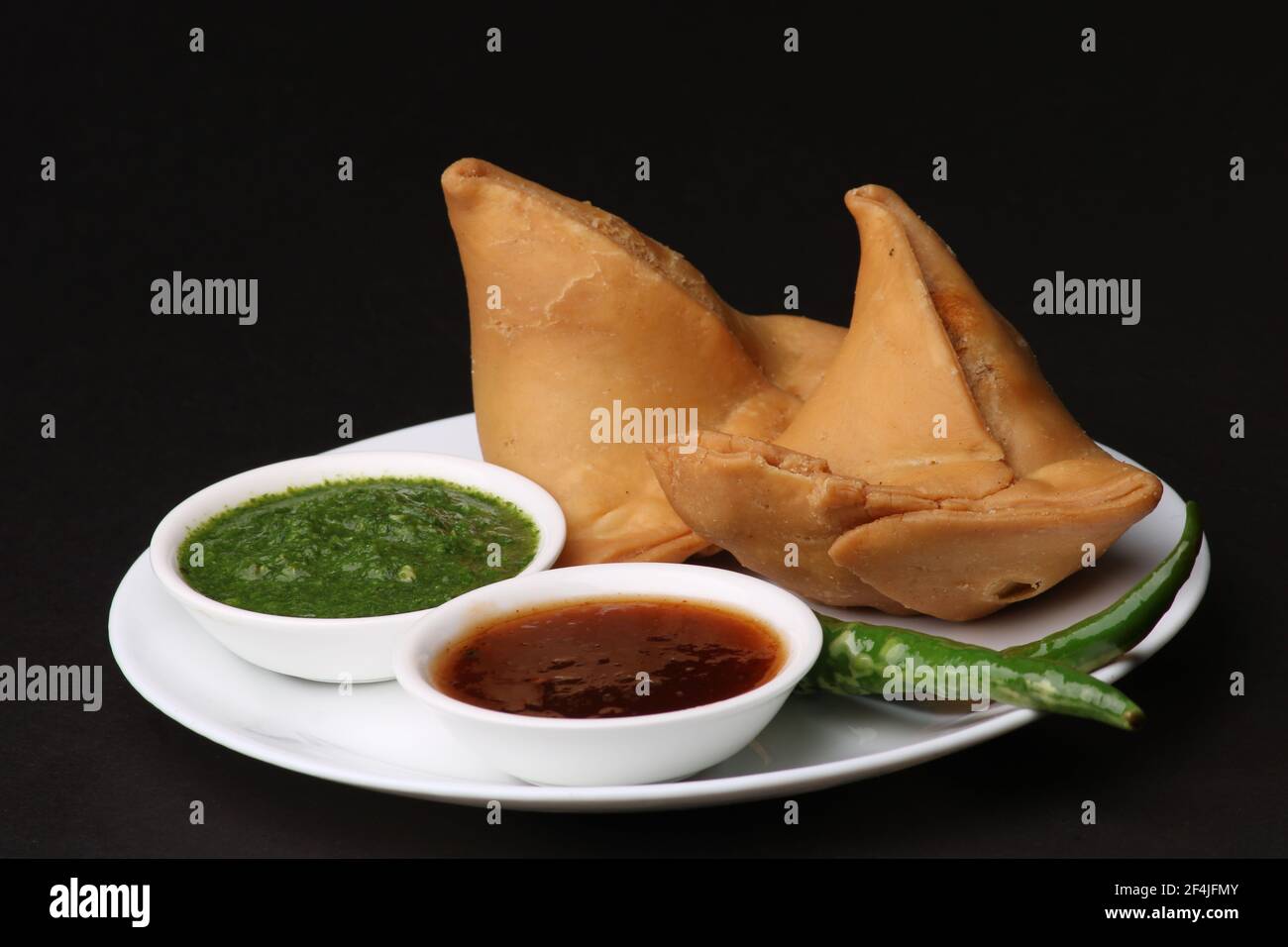 Snack indiano speziato e delizioso samosa fatto in casa, servito con chutney di tamarindo verde. Foto Stock