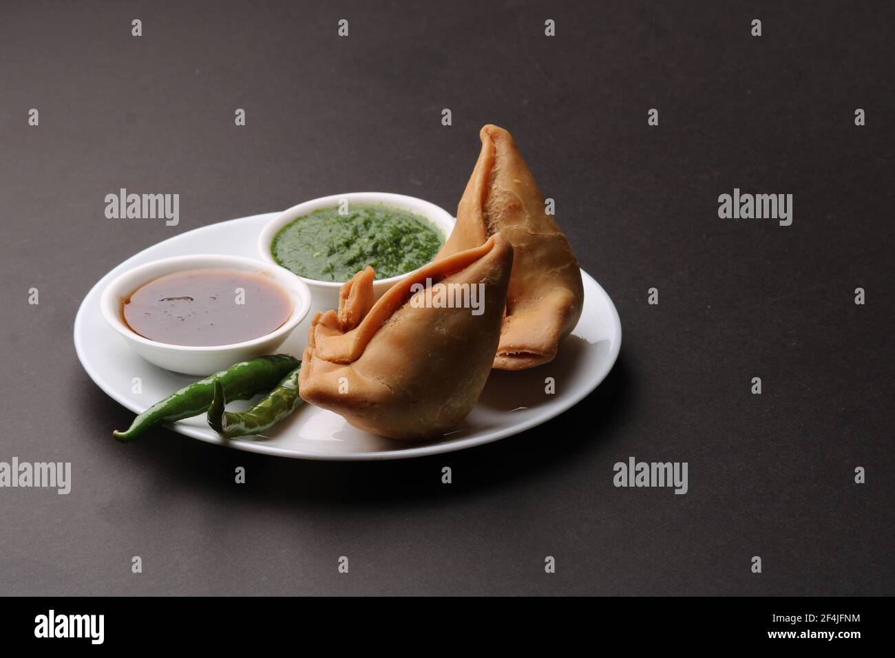 Snack indiano speziato e delizioso samosa fatto in casa, servito con chutney di tamarindo verde. Foto Stock