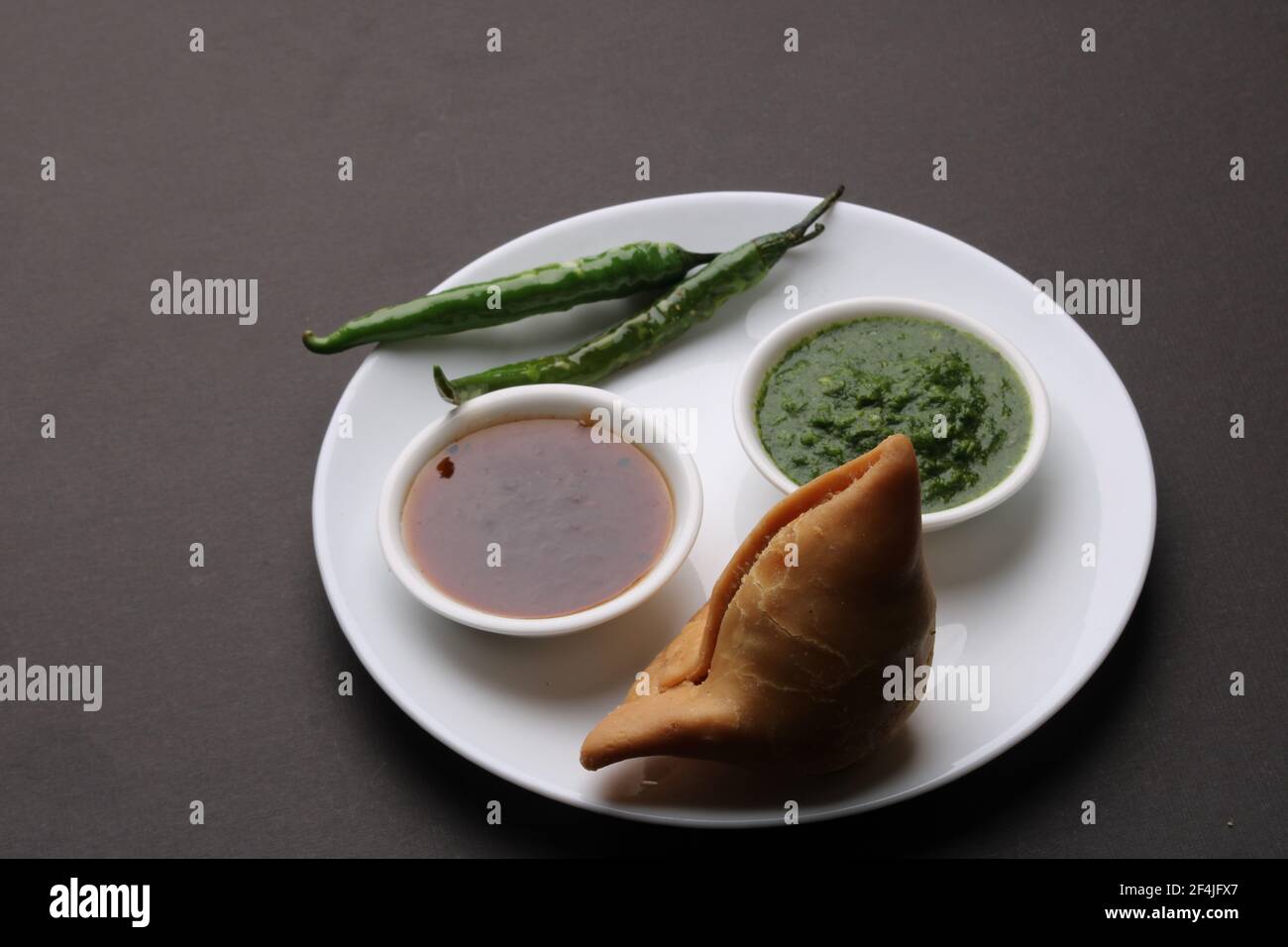 Snack indiano speziato e delizioso samosa fatto in casa, servito con chutney di tamarindo verde. Foto Stock