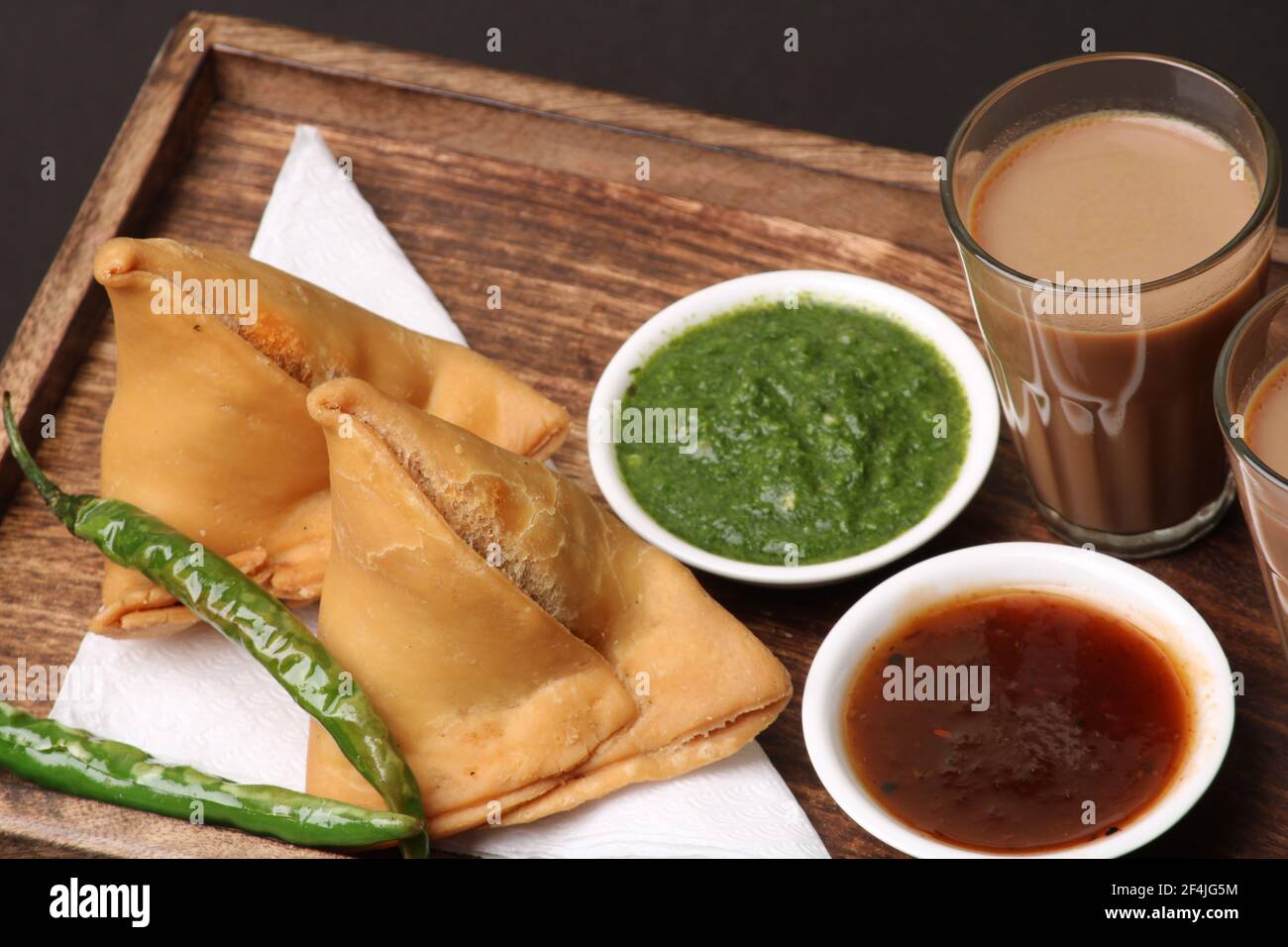 Snack indiano in casa speziato e deliziosa samosa servita con verde, tamarindo chutney taglio tè masala, chai, Foto Stock