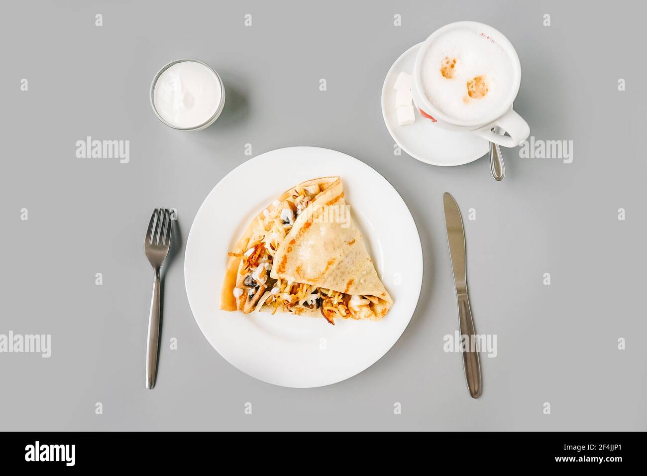 Persona che mangia crepes con ripieno. Gustosa colazione su sfondo grigio. Vista dall'alto. Foto Stock