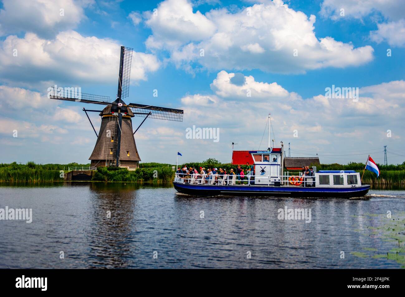 Kinderdijk, Paesi Bassi - 22 giugno 2019: Imbarcazione turistica che naviga sui canali a Kinderdijk, Paesi Bassi, con un tradizionale mulino a vento olandese Foto Stock