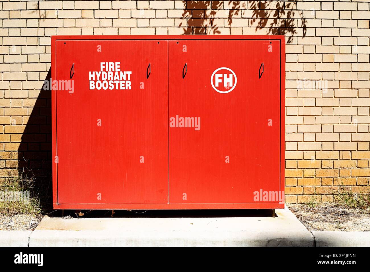 Armadio ausiliario idrante antincendio rosso contro una parete di mattoni su una giornata di sole Foto Stock