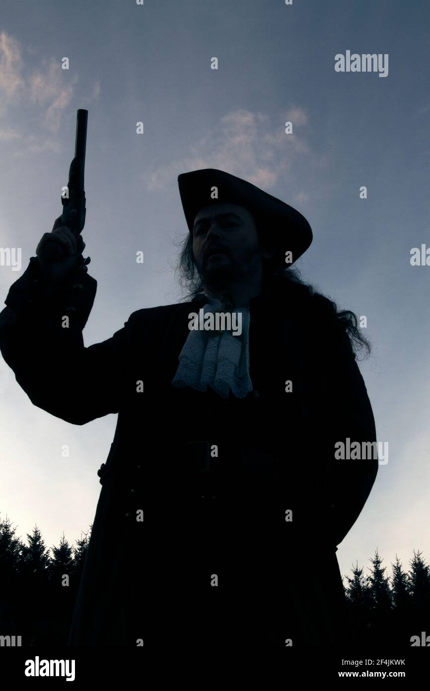 Buccaneer Holding Pistol contro gli alberi Silhouette Foto Stock