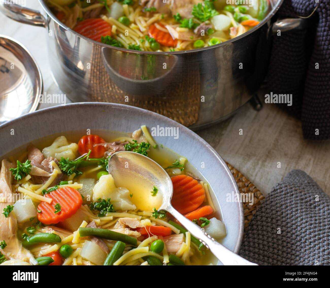 zuppa di noodle di pollo fresca e cucinata in casa con verdure primaverili servito su un piatto su un tavolo con pentola in lo sfondo Foto Stock