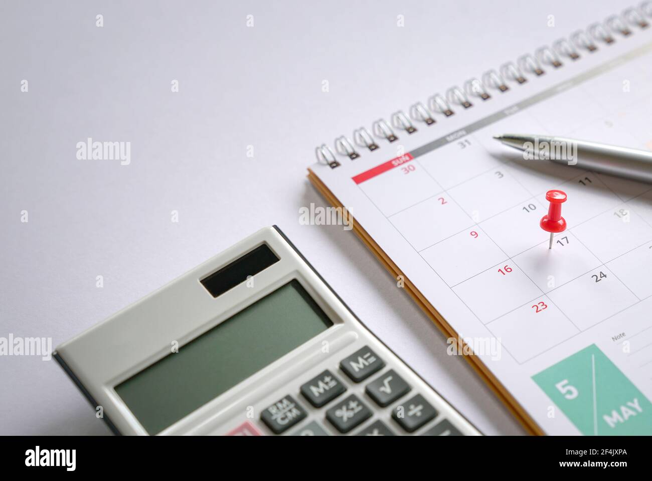 Pulsante rosso sul calendario di maggio 17 con penna e calcolatrice sulla parte superiore del tavolo. Promemoria del nuovo giorno fiscale per il 2021. Foto Stock