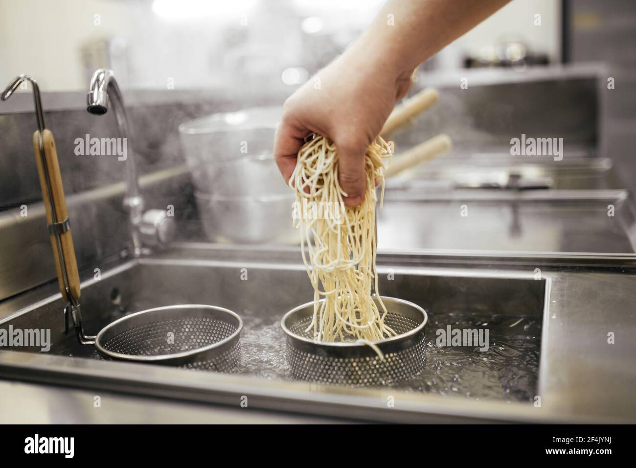 Cuocere gli spaghetti d'uovo nei cestini bollenti Foto Stock
