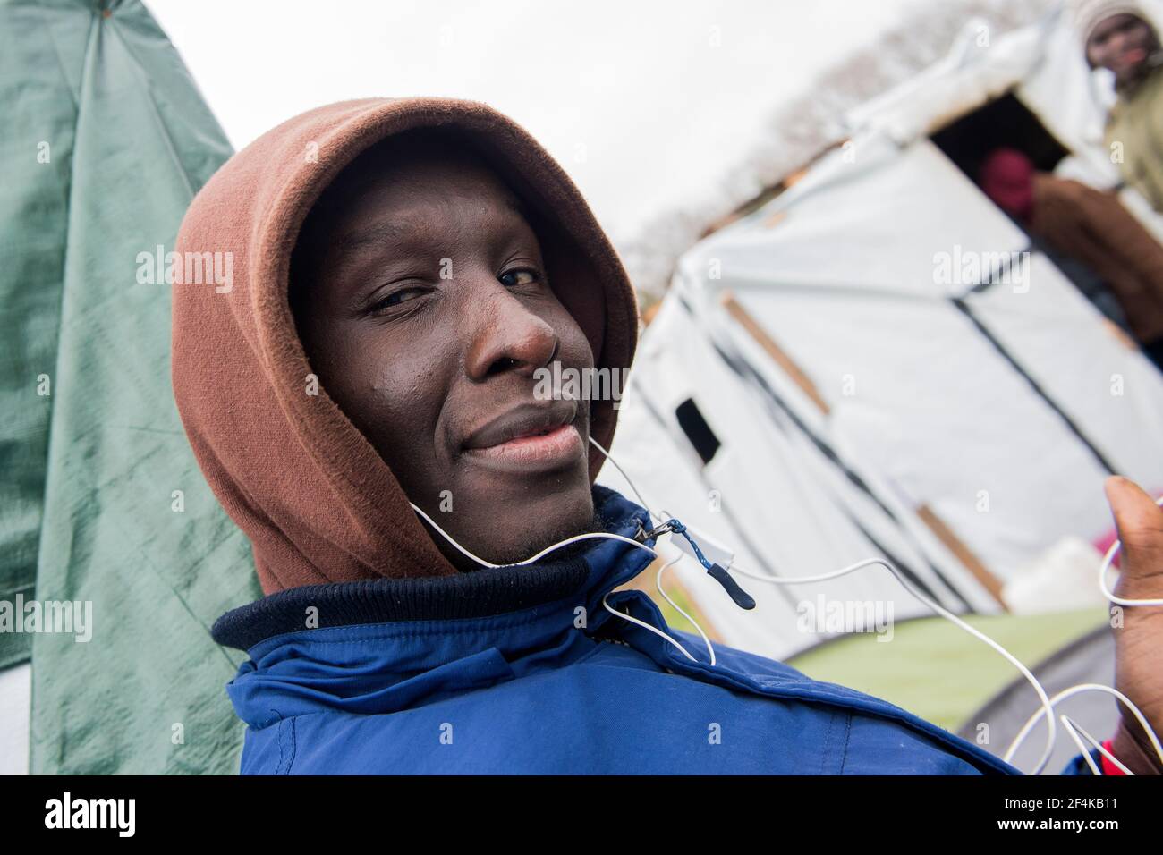 Calais, Francia. Sudani immigrato illegale nella giungla di Calais indossando una felpa e ascoltando musica, in attesa della sua possibilità di viaggiare nel Regno Unito. Foto Stock
