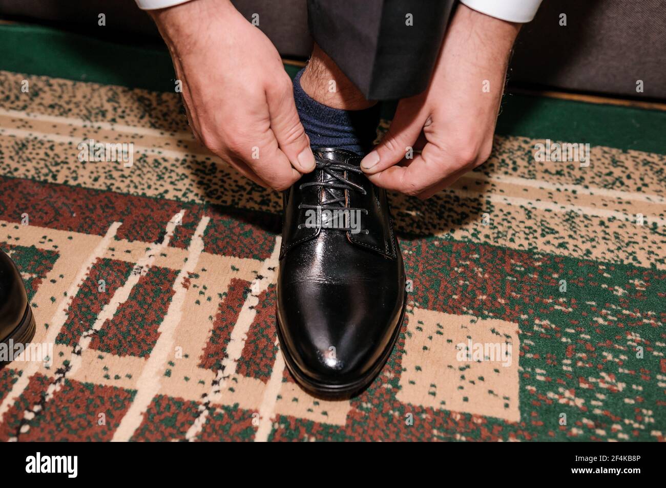 Il ragazzo sta legando i lacci sulle scarpe classiche nere. Lo sposo  indossa scarpe belle e le lega le sue scarpe Foto stock - Alamy