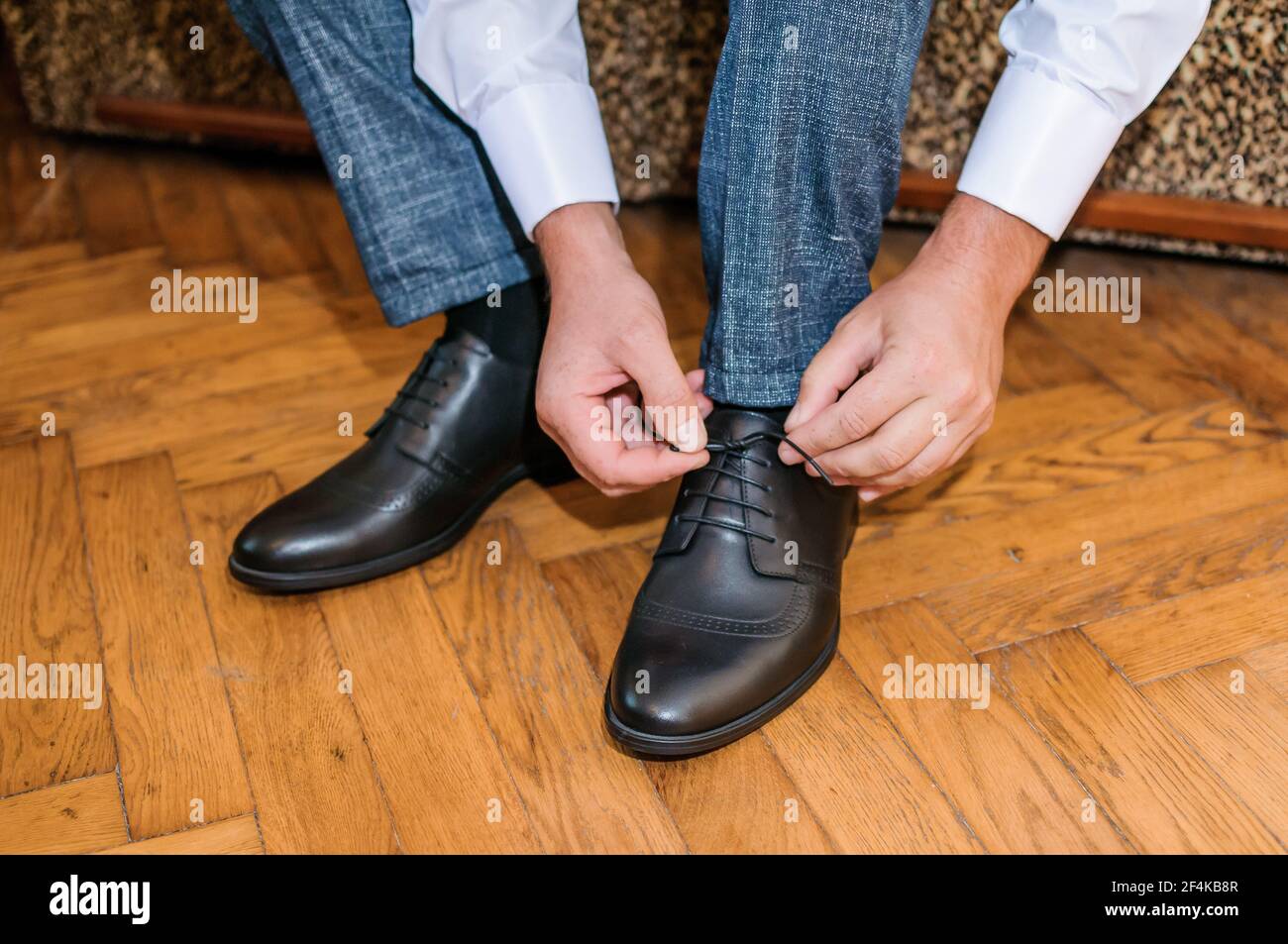 Il ragazzo sta legando i lacci sulle scarpe classiche nere. Lo sposo  indossa scarpe belle e le lega le sue scarpe Foto stock - Alamy