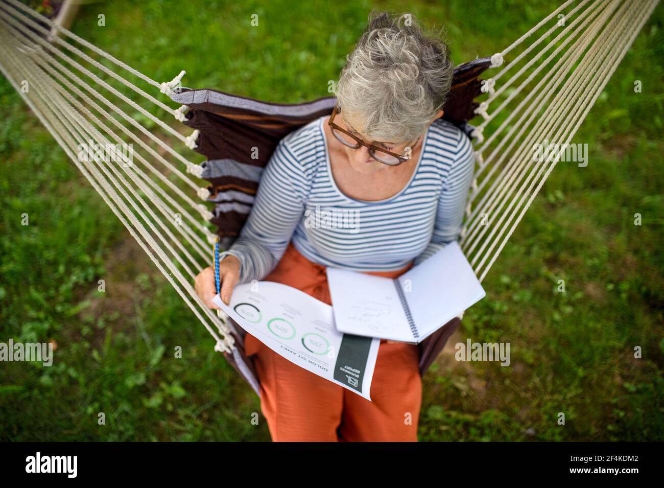Vista dall'alto della donna anziana attiva che lavora all'aperto in giardino, concetto di home Office. Foto Stock