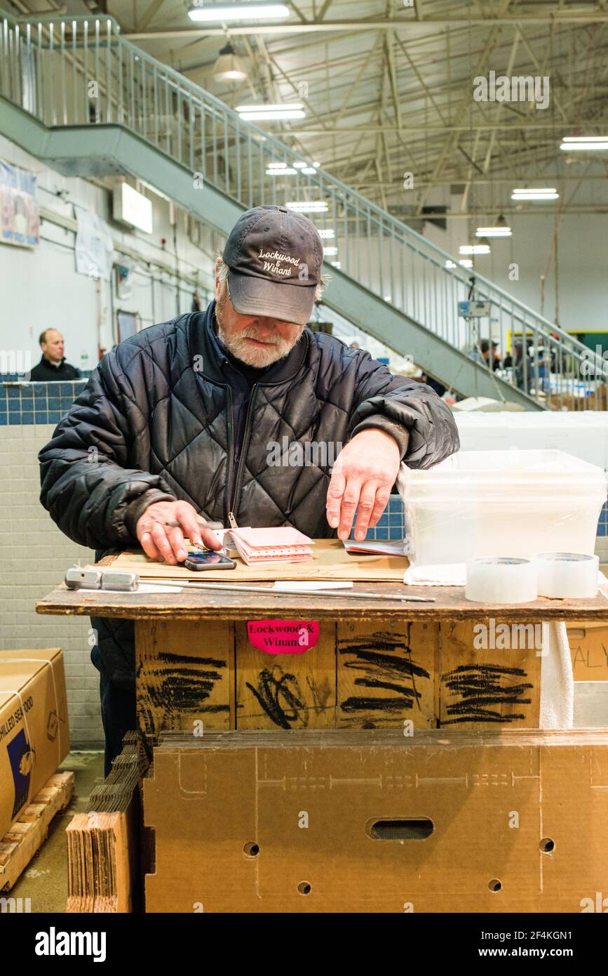 New York City, Stati Uniti. L'impiegato di stallo del mercato all'ingrosso che crunching i numeri dopo la conclusione di un ordine al mercato del pesce di New Fulton, Hunts Point, il Bronx. Foto Stock