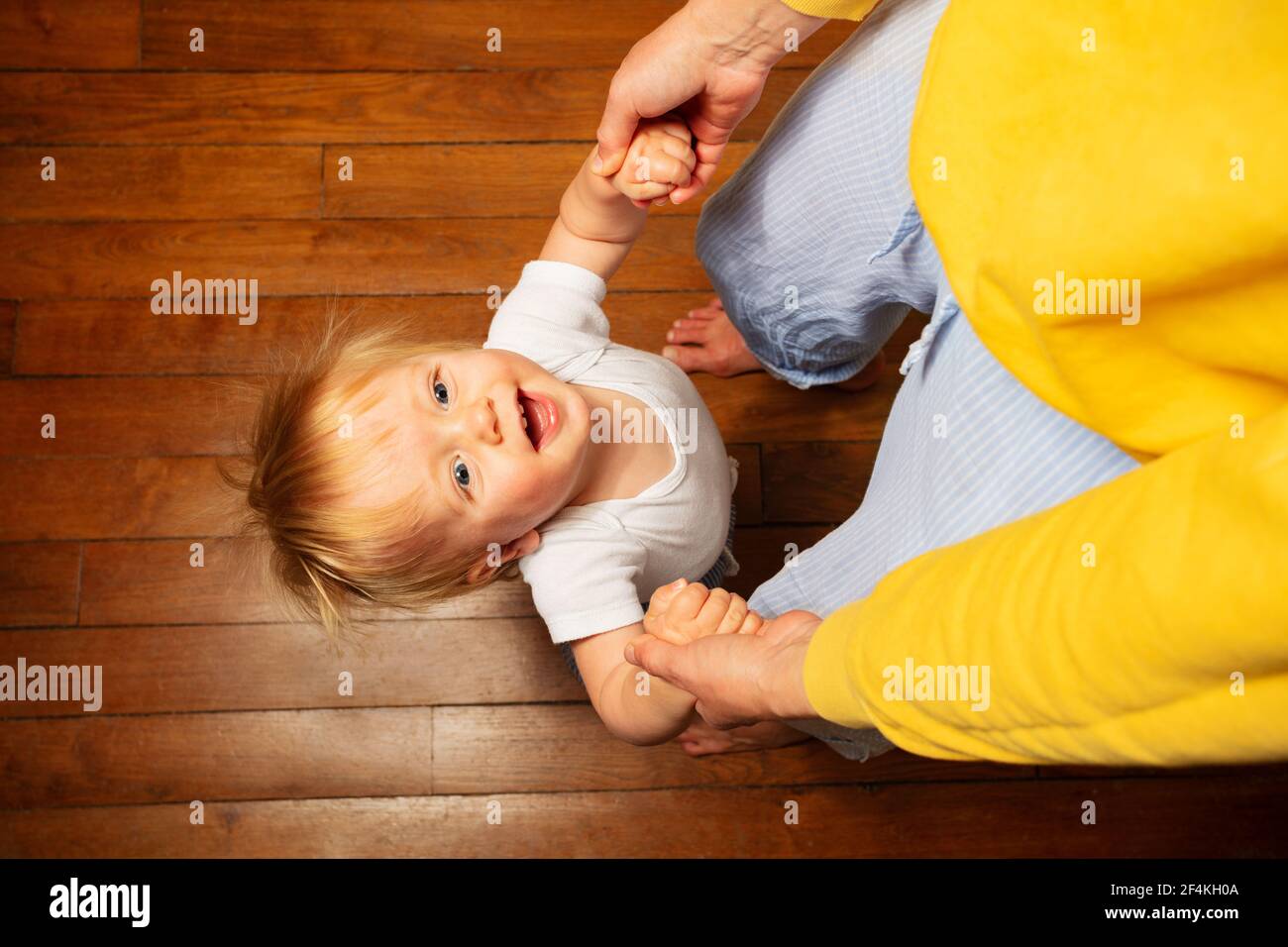 Il ragazzo toddler tiene le mani della mamma guardando su sorridente Foto Stock