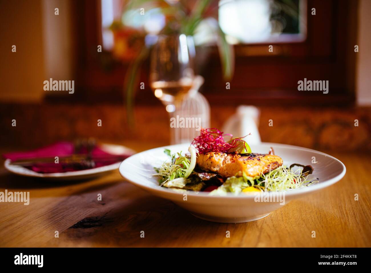 Cibo del ristorante con ingredienti freschi - salmone alla griglia e fresco insalata nel ristorante di lusso con un bicchiere di vino e posate Foto Stock