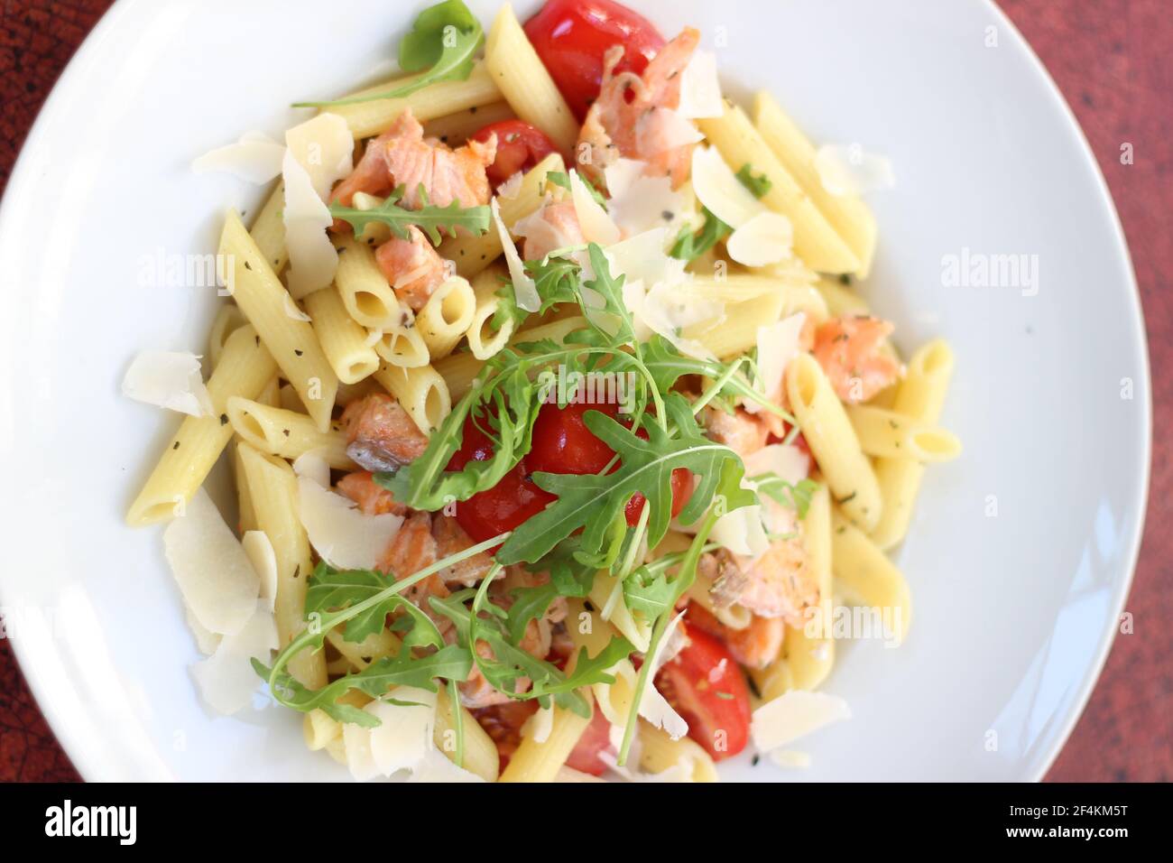 Cibo da ristorante con ingredienti freschi - pasta con pomodori, salmone, parmigiano e rucola fresca Foto Stock