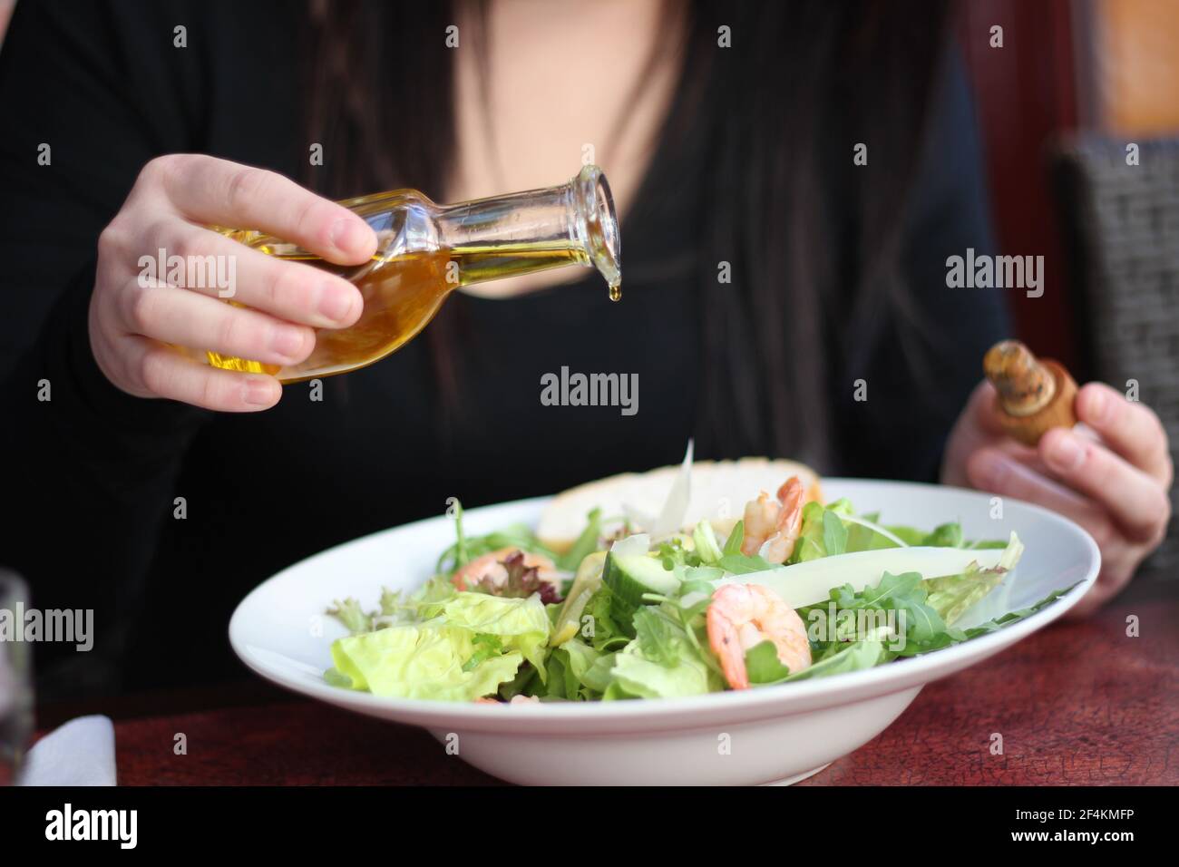 Cibo da ristorante con ingredienti freschi - insalata con gamberi, parmigiano e olio d'oliva che scorre Foto Stock