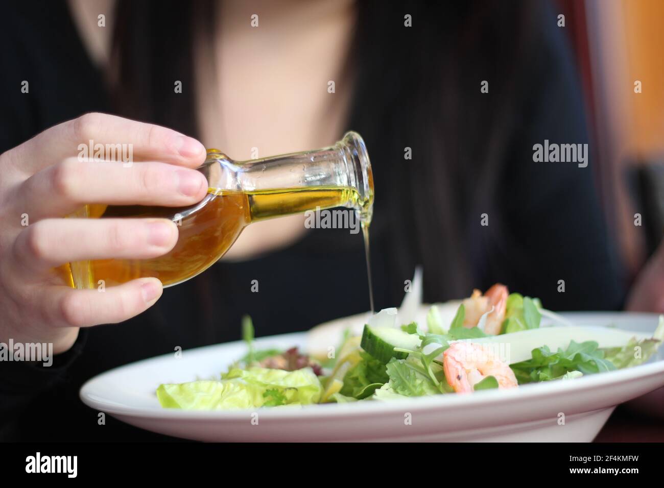 Cibo da ristorante con ingredienti freschi - insalata con gamberi, parmigiano e olio d'oliva che scorre Foto Stock