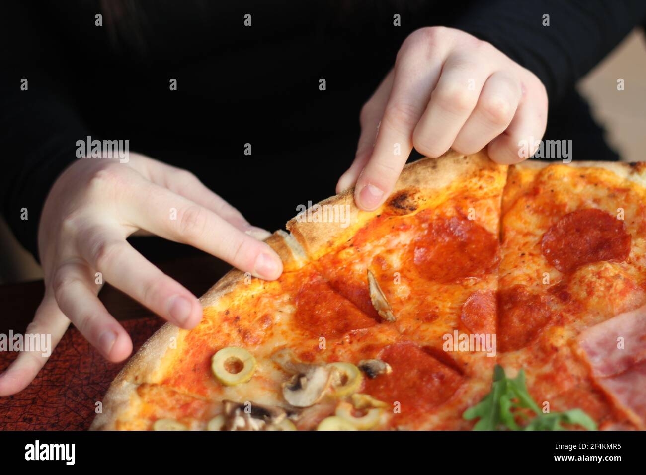 Pizza con le mani della ragazza - cibo da ristorante con ingredienti freschi Foto Stock