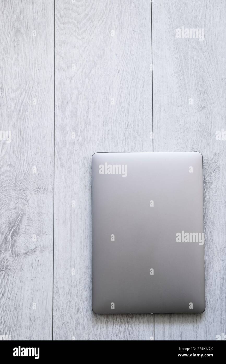 Un lap top su un legno bianco - scrivania o pavimento, spazio di copia, tagliato, dall'alto, metallo, zinco, nessuna gente Foto Stock