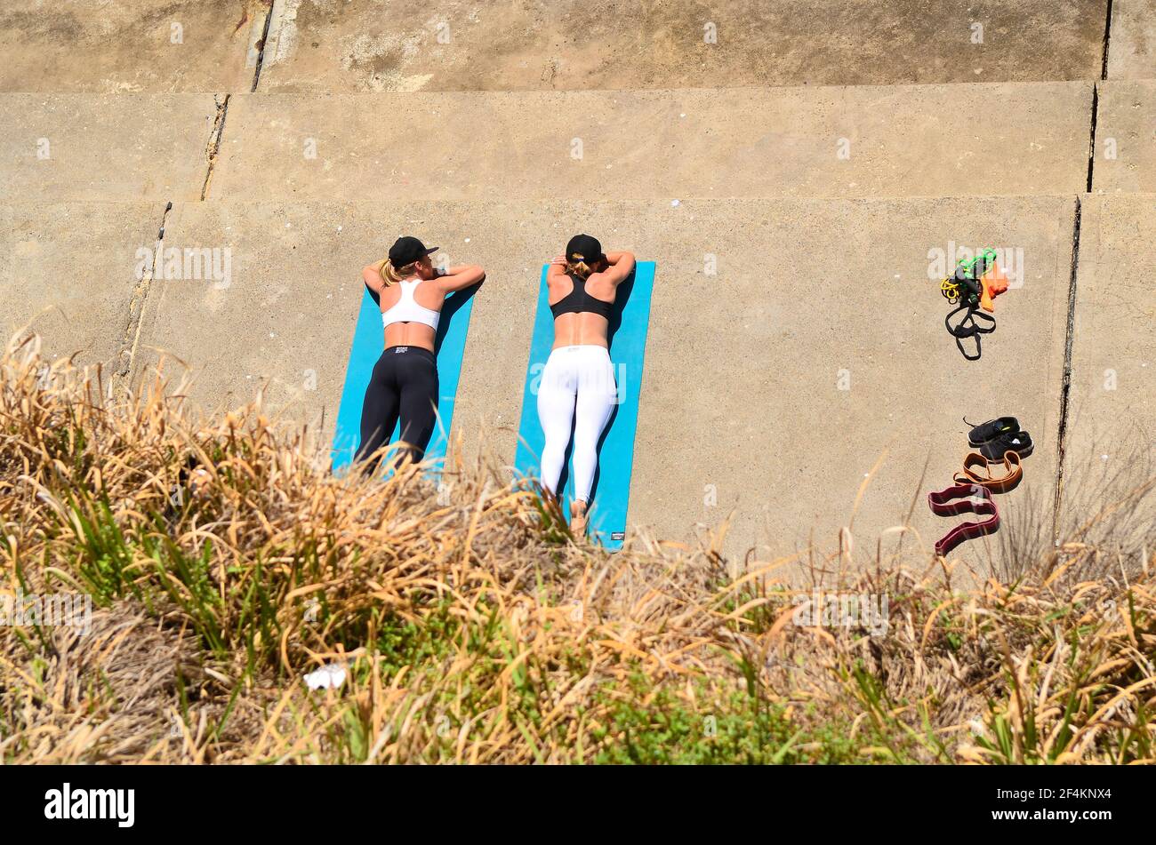 Sydney, NSW, Australia - 31 ottobre 2017: Due donne non identificate che si rilassano dopo esercizi ginnici su una piattaforma a Bondi Beach Foto Stock