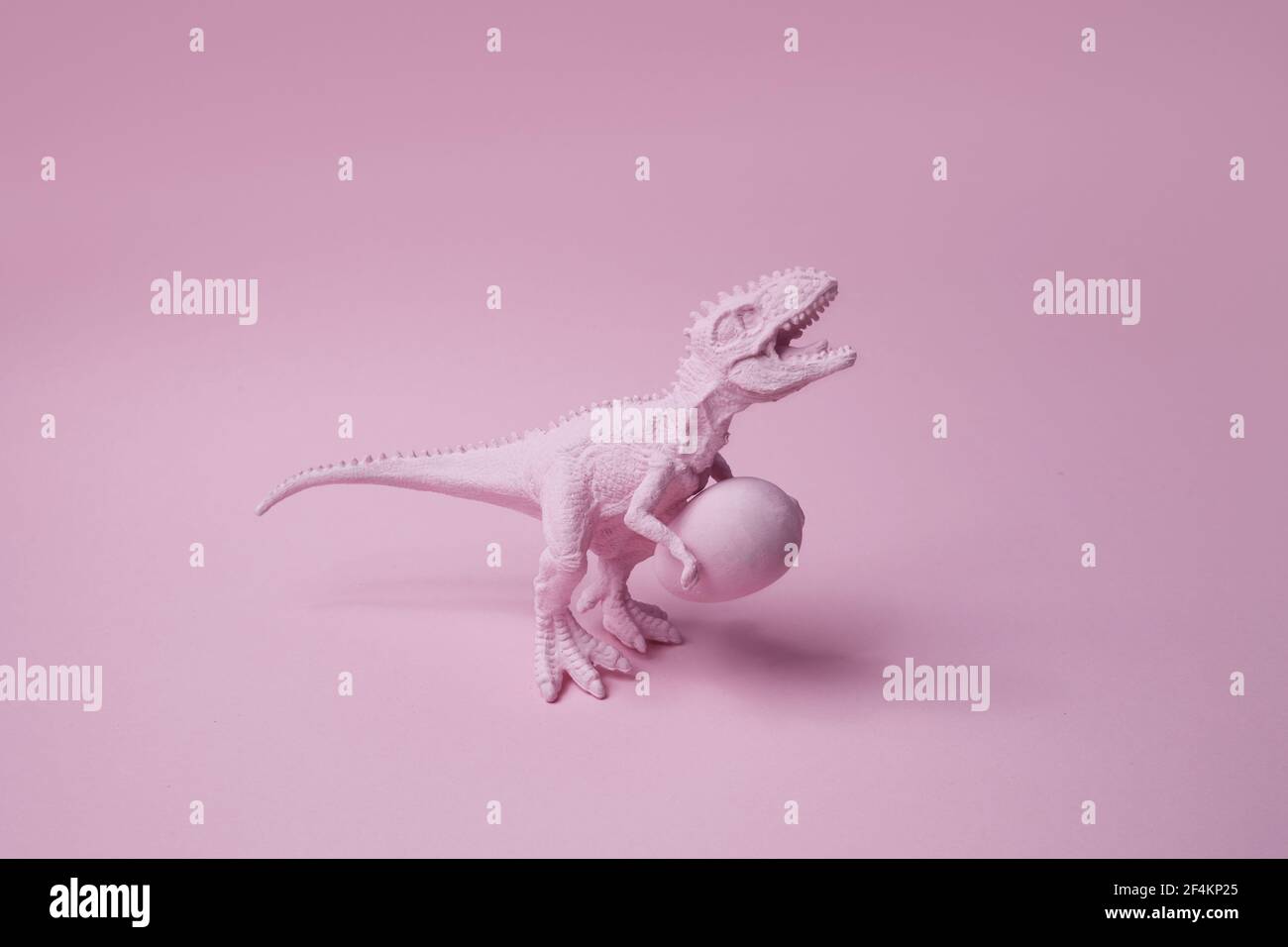 Dinosauro T rex con uovo di pasqua su sfondo rosa. Divertente Ester greating. Foto Stock