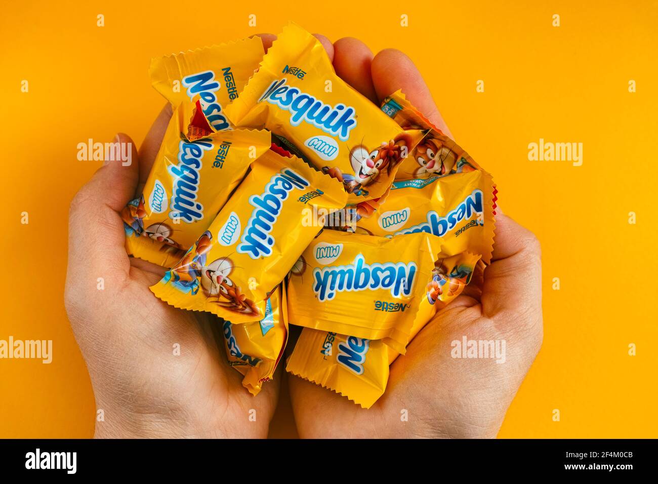 Tambov, Federazione Russa - 30 Gennaio 2021 Palme femminili piene di mini caramelle Nesquik di Nestle. Sfondo giallo. Foto Stock