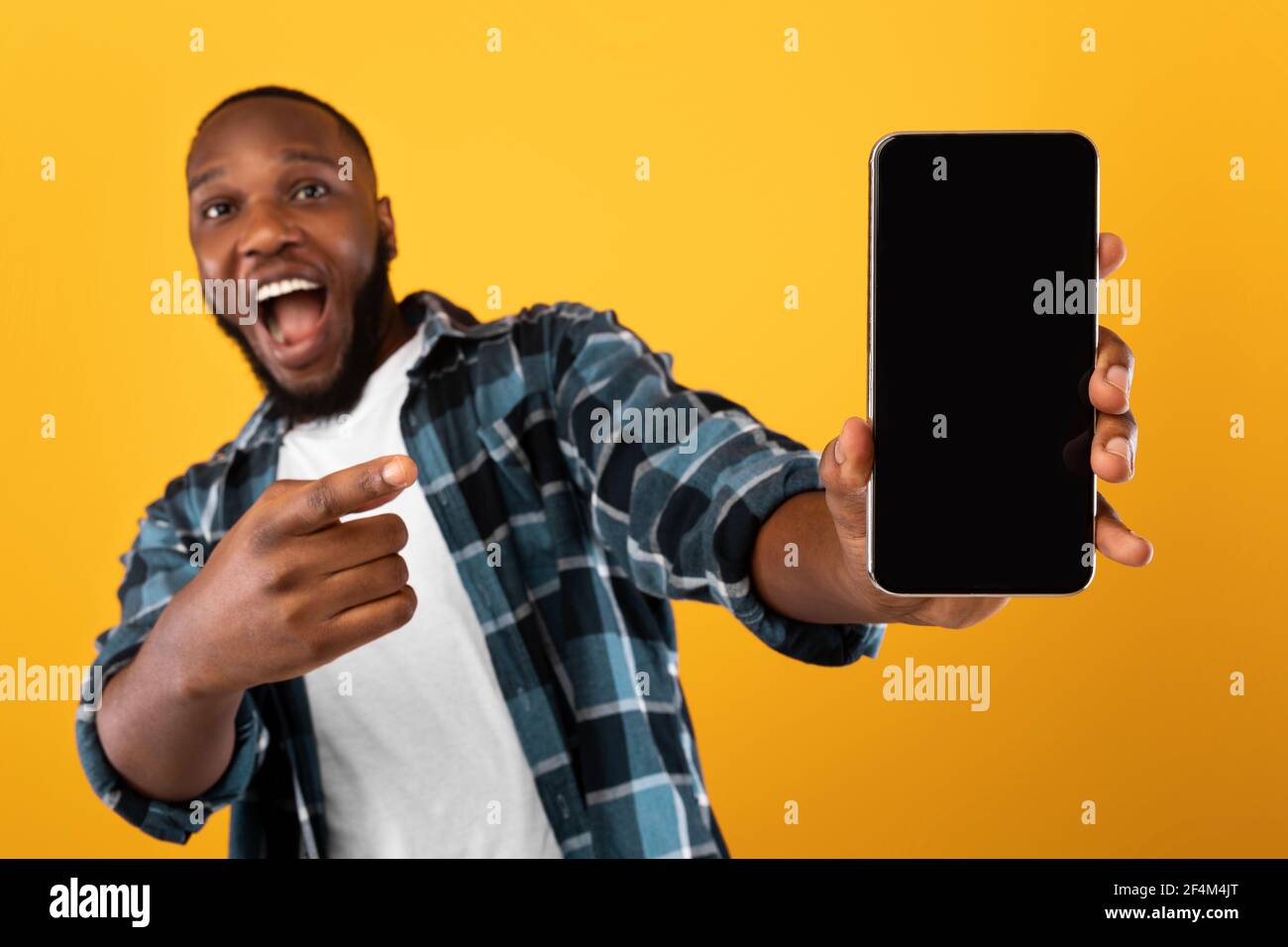 Ecited Black Guy mostra la schermata del telefono cellulare su sfondo giallo Foto Stock