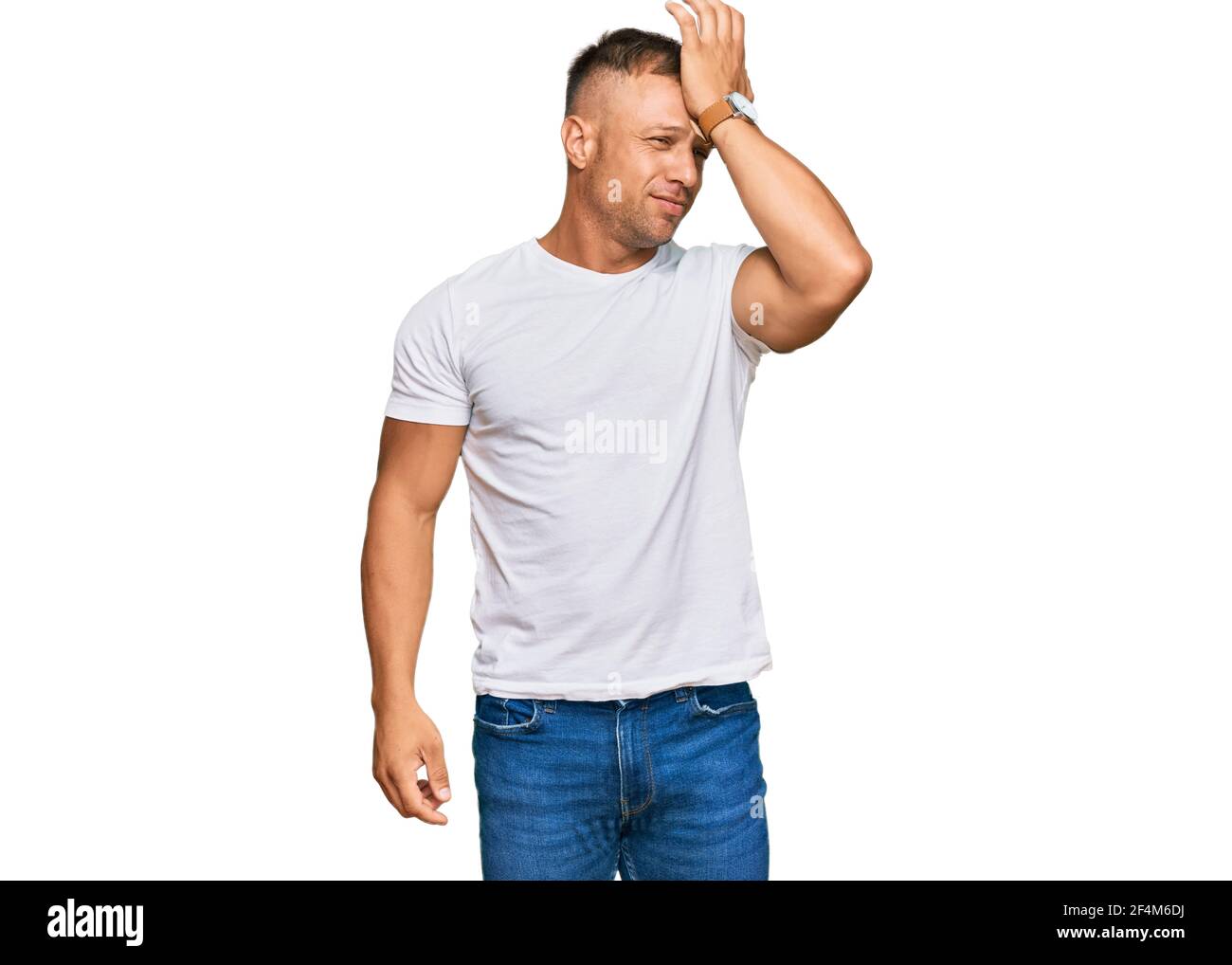 Bel muscolo uomo che indossa casual tshirt bianca sorpreso con mano sulla testa per errore, ricordare errore. dimenticato, cattivo concetto di memoria. Foto Stock