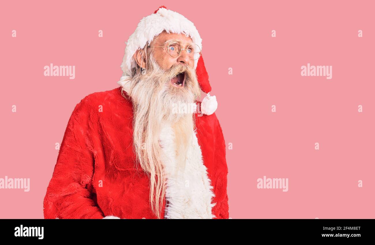 Vecchio uomo anziano con capelli grigi e barba lunga con costume tradizionale di babbo natale arrabbiato e pazzo urlando frustrato e furioso, gridando con ang Foto Stock