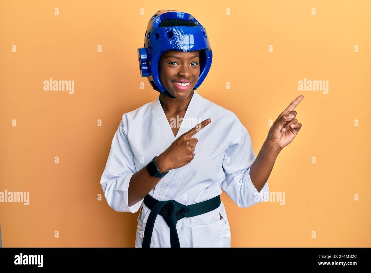 Giovane afroamericana che indossa il taekwondo kimono e casco di protezione  sorridendo e guardando la fotocamera con due mani e le dita fino al Foto  stock - Alamy