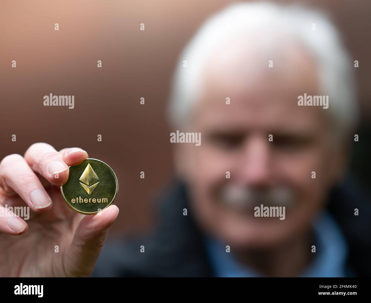 Simbolo di Ethereum come investimento nel piano di pensionamento. Uomo anziano che tiene una moneta di Ethereum. Foto Stock