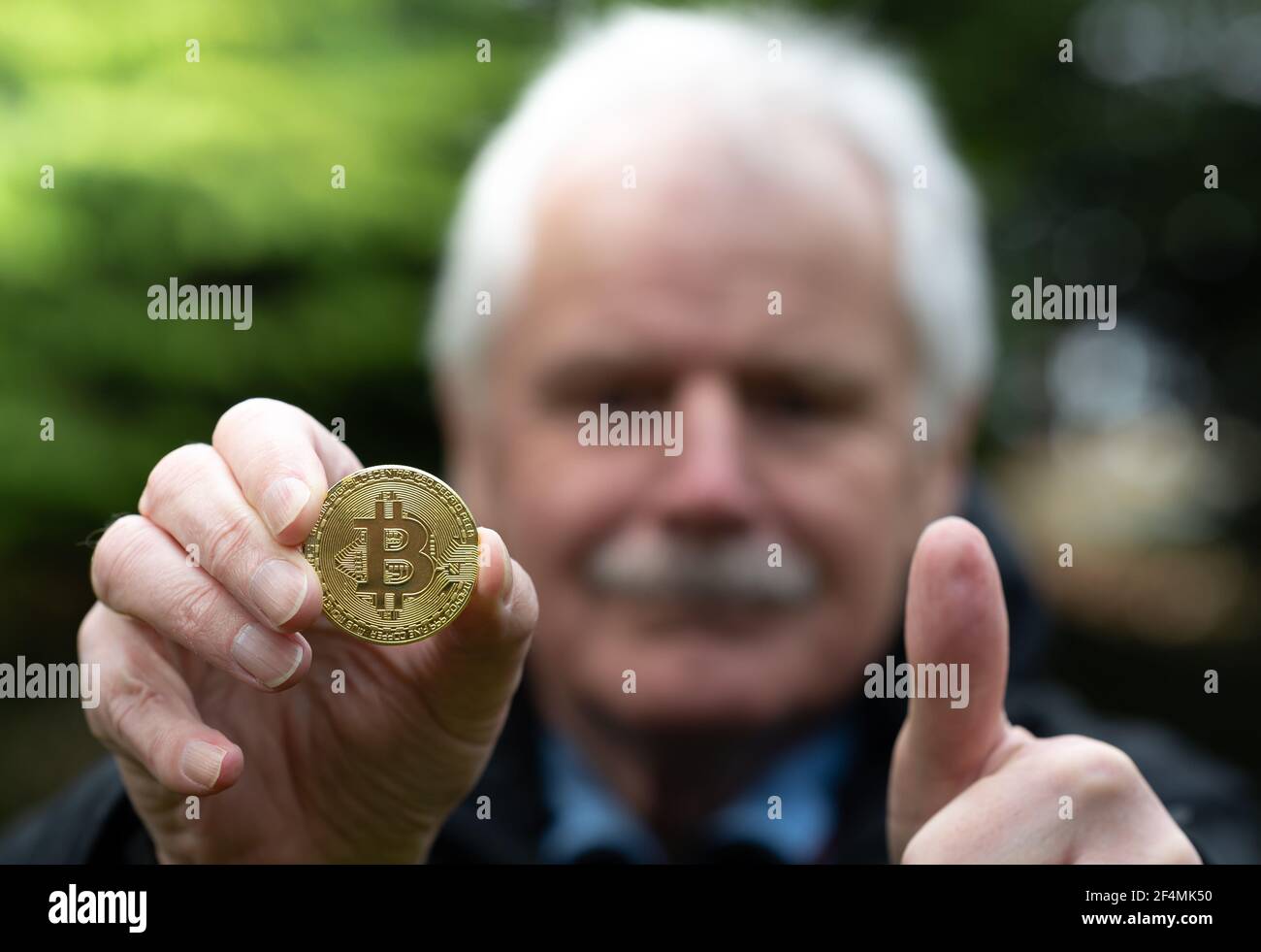 Simbolo di Bitcoin come investimento di piano di pensionamento. Vecchio uomo che tiene un Bitcoin. Foto Stock