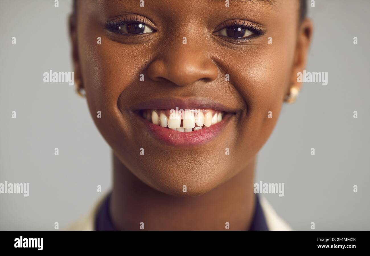 Primo piano ritratto di una giovane donna nera felice con un incantevole sorriso bianco Foto Stock