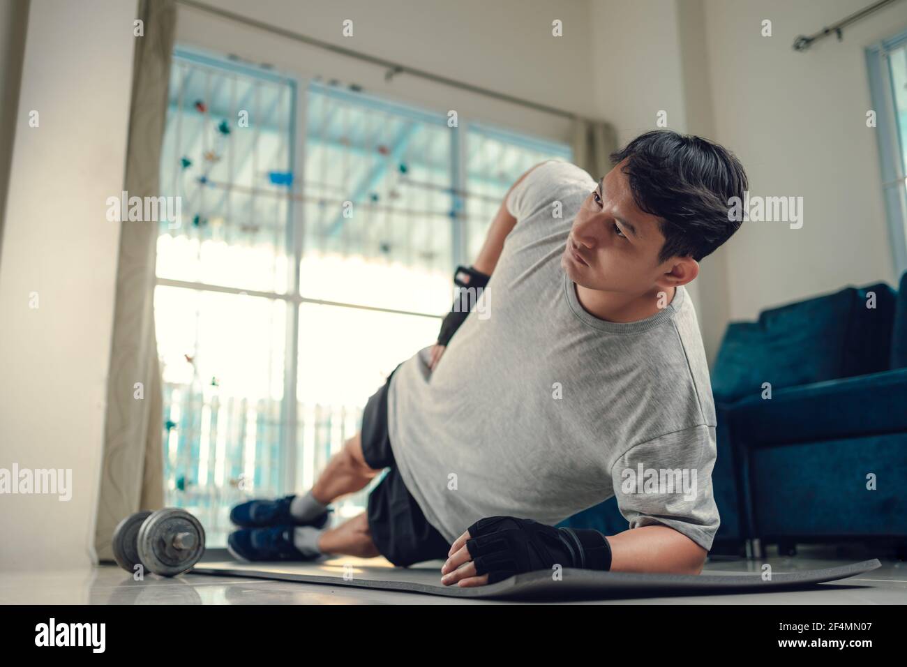 Giovane uomo che fa esercizi addominali su tappetino yoga in soggiorno a  casa. Concetto di fitness, allenamento e traning a casa Foto stock - Alamy