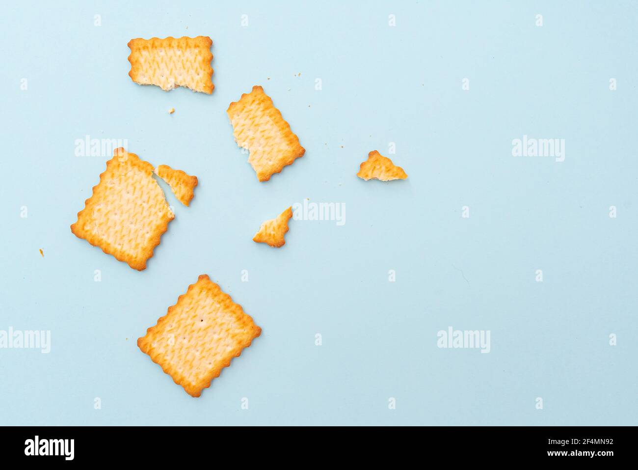 Biscotti secchi rotti su sfondo blu, vista dall'alto, disposizione Foto Stock