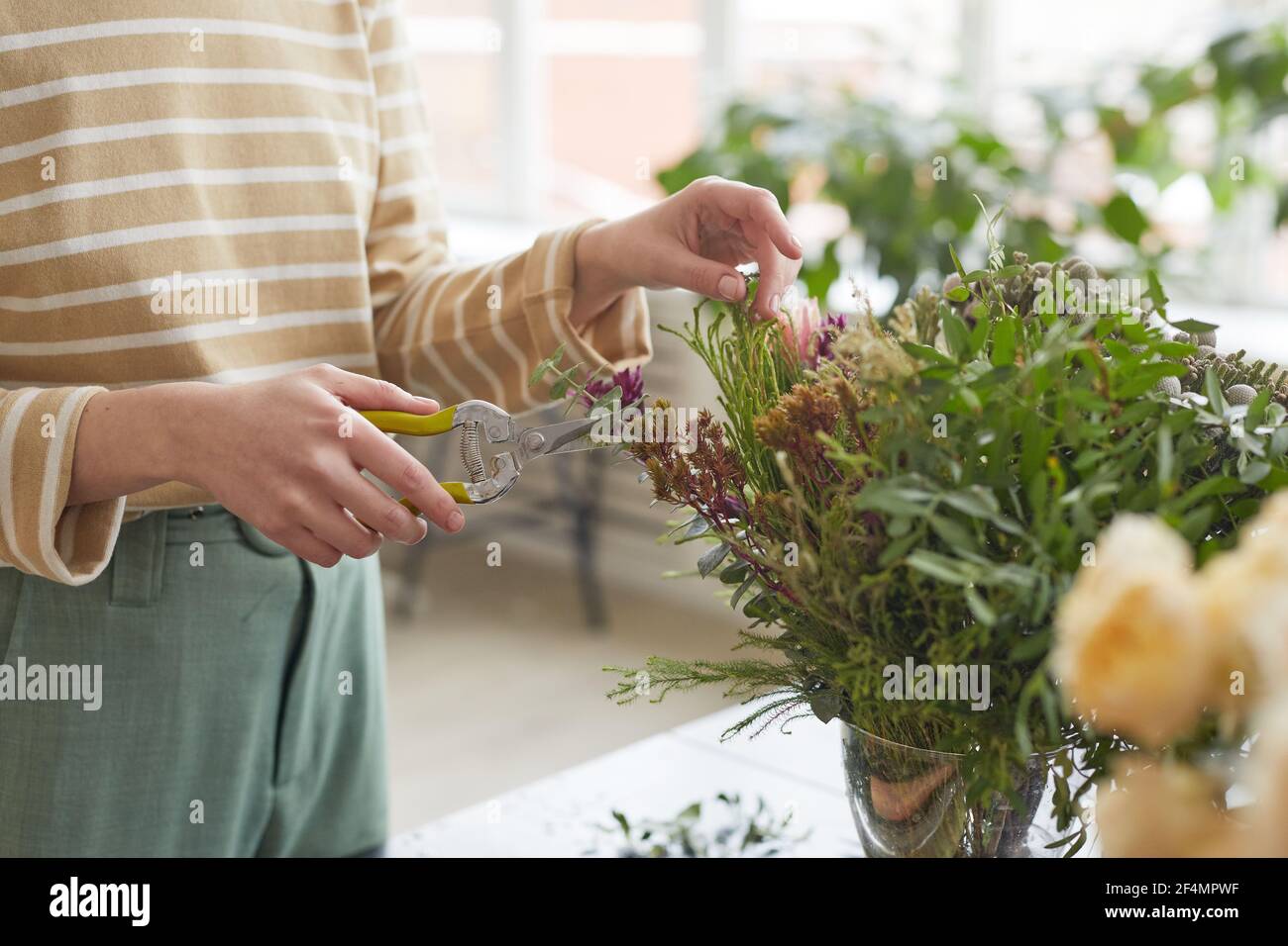 Primo piano di piante da taglio donna irriconoscibile mentre si organizzano composizioni floreali in officina, spazio di copia Foto Stock