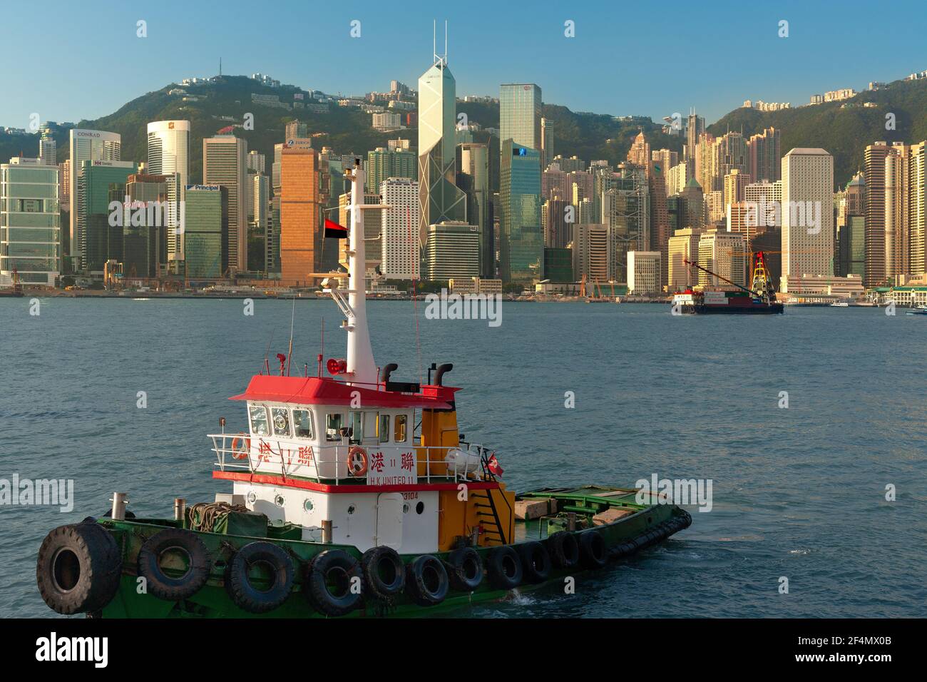 Isola di Hong Kong, Hong Kong, Cina, Asia - Tugboat di fronte al moderno skyline di Hong Kong. Foto Stock