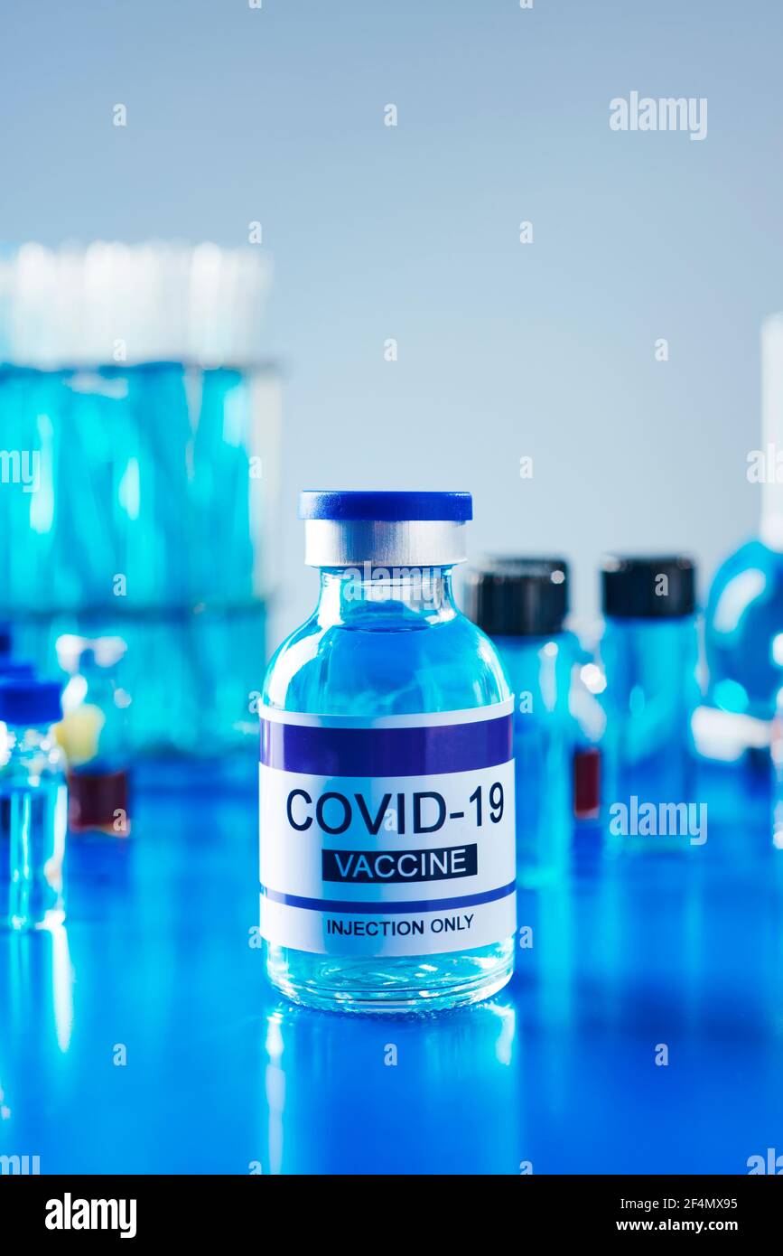 chiusura di un flaconcino simulato del vaccino covid-19 su una tavola blu, in laboratorio Foto Stock