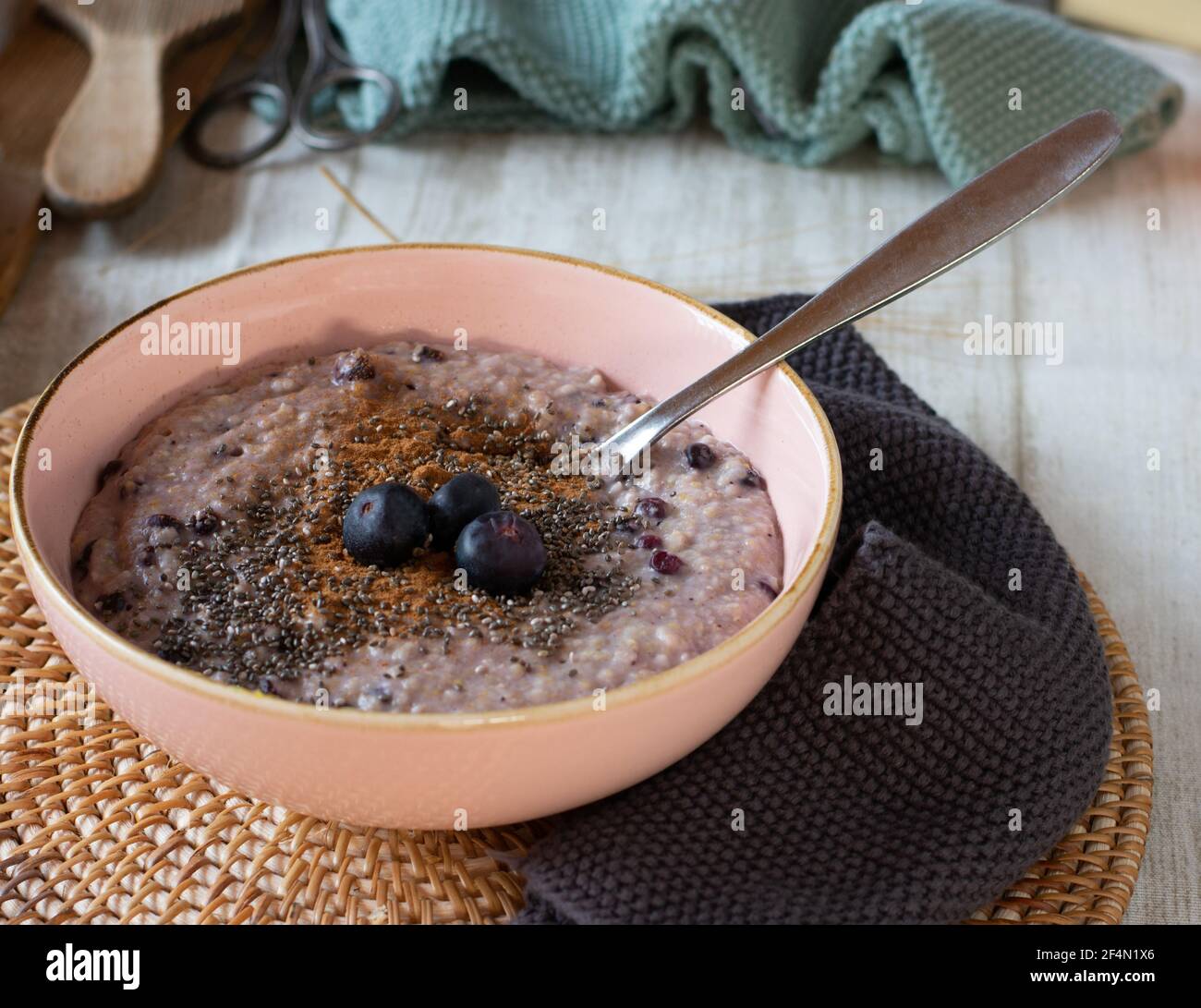 porridge di mirtillo fresco cotto con semi di chia e cinimon serviti in una ciotola rosa con cucchiaio isolato su tavola di legno Foto Stock