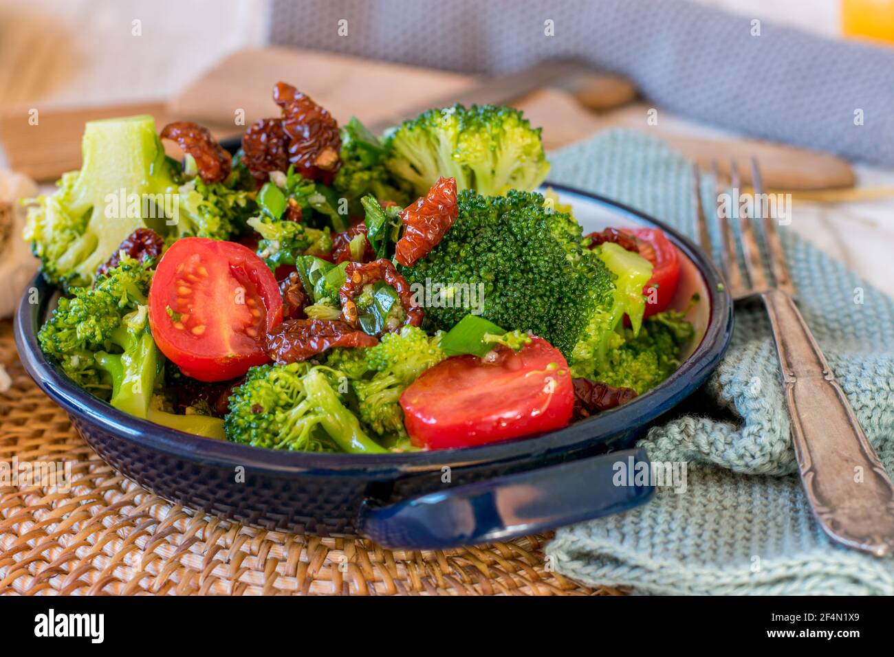 insalata di broccoli con pomodori freschi e secchi, aglio, cipolle rosse marinate in aceto balsamico e condimento con olio d'oliva serviti in una ciotola Foto Stock