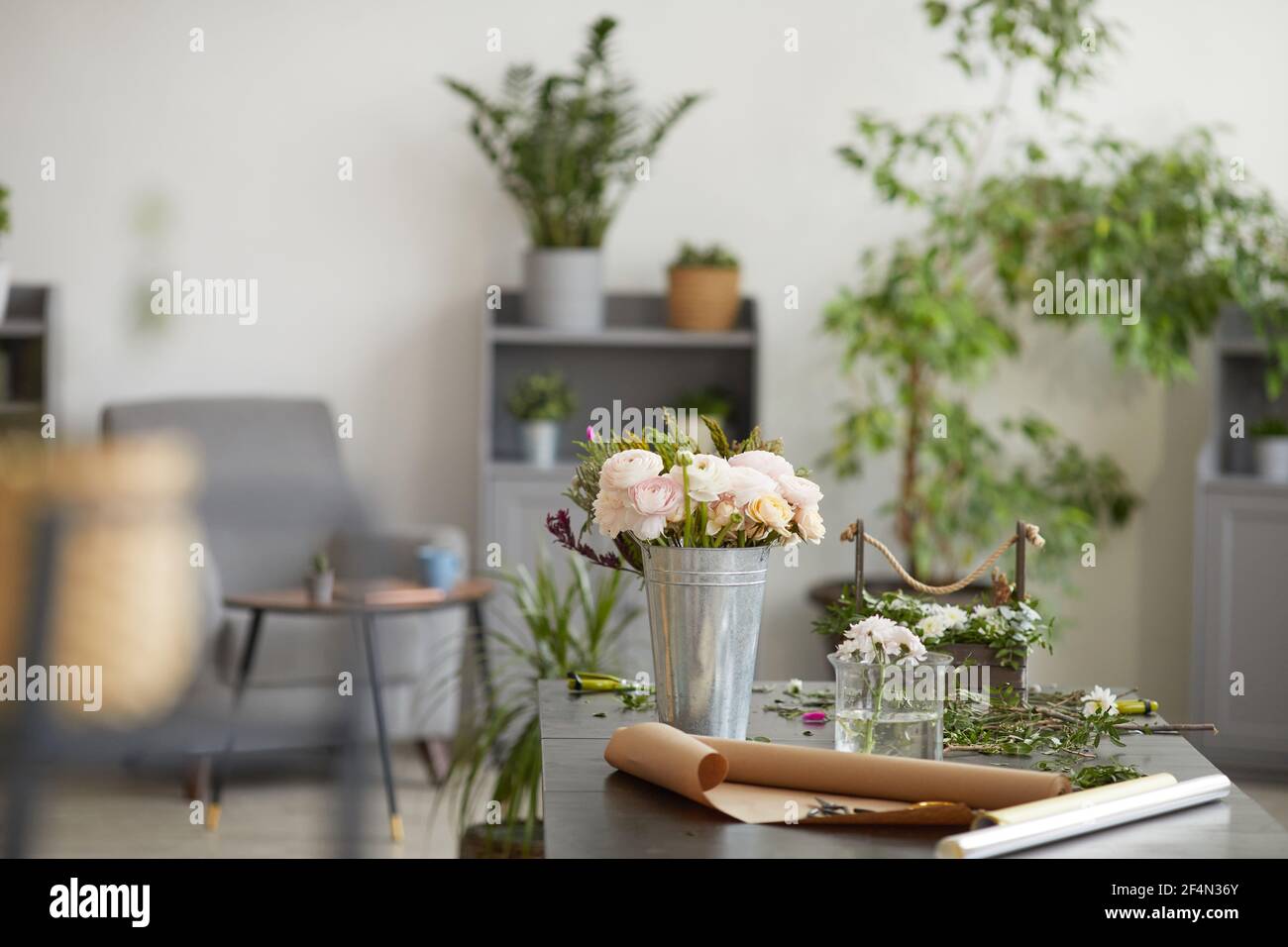 Immagine di sfondo di bellissimi fiori in secchi e vasi sul tavolo in laboratorio fiorista decorato da piante verdi, spazio copia Foto Stock