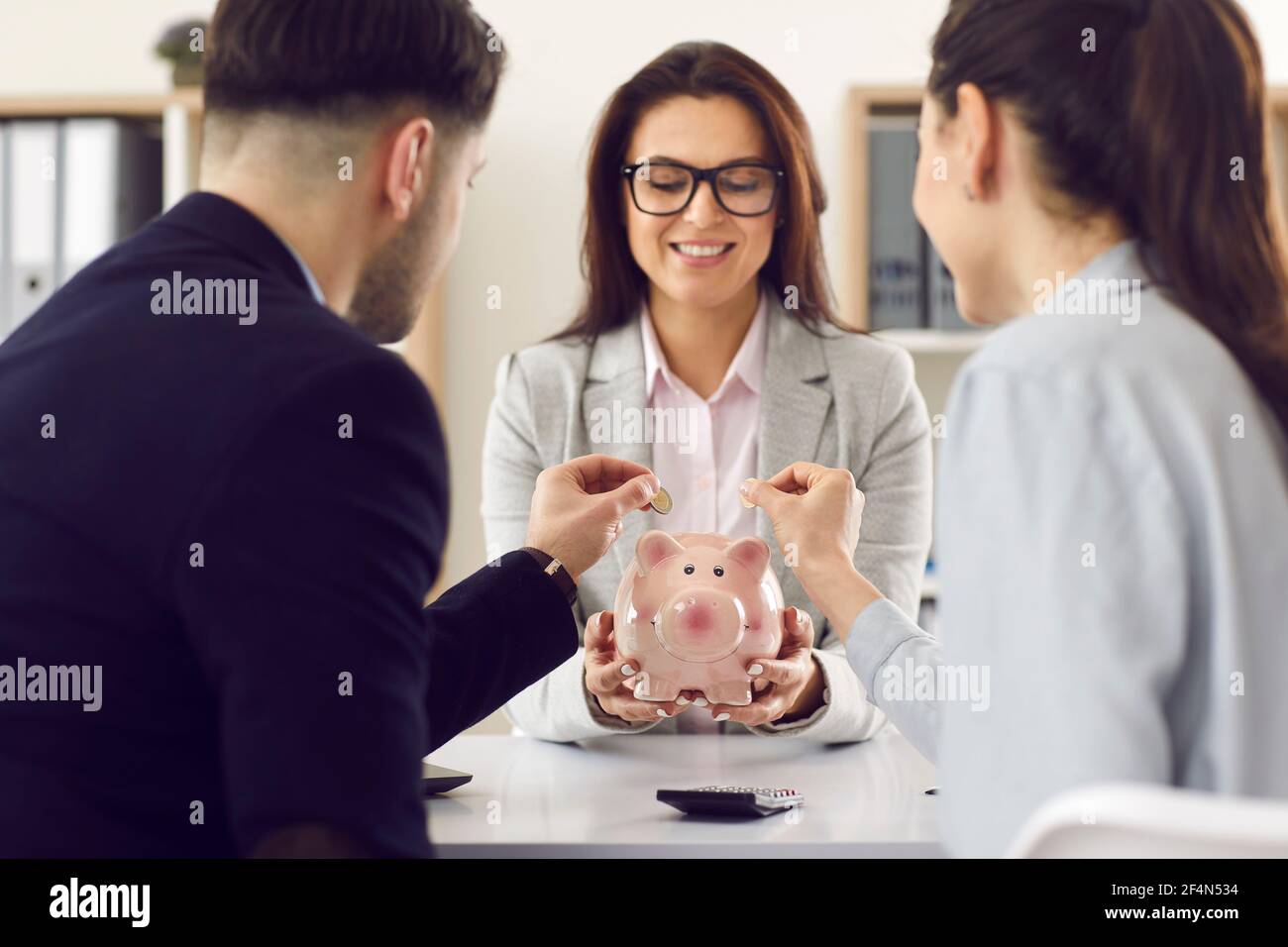 Closeup piggybank in caucasica donna banca manager mani e coppia mettere moneta Foto Stock