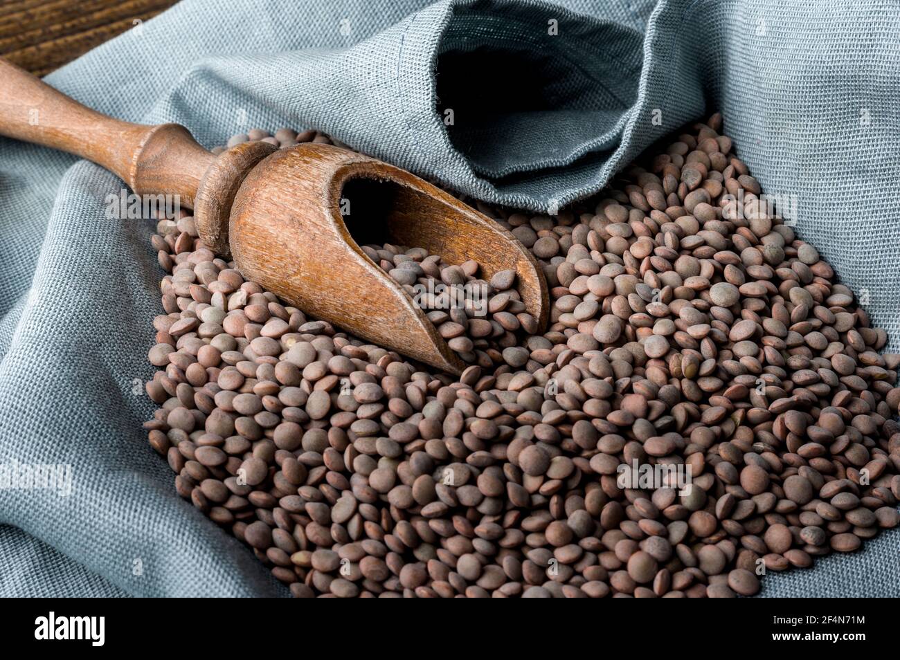 Colpo di closeup di un mucchio di lenticchie e di un legno raccogliere in un sacco Foto Stock