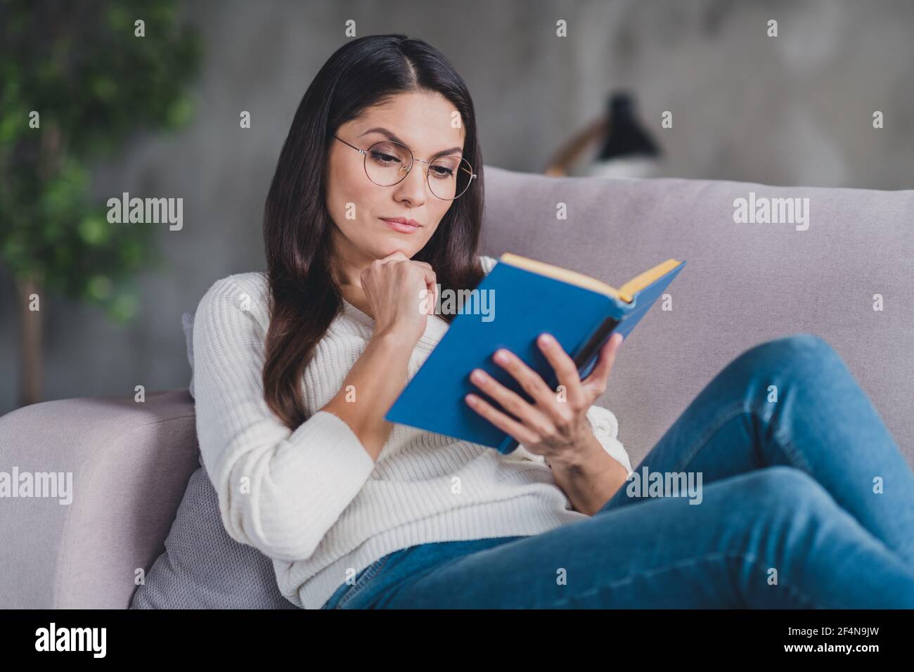 Foto di mentalita seria ragazza riposo lettino letto libro di testo indossare occhiali da vista bianco pullover in soggiorno casa al chiuso Foto stock Alamy